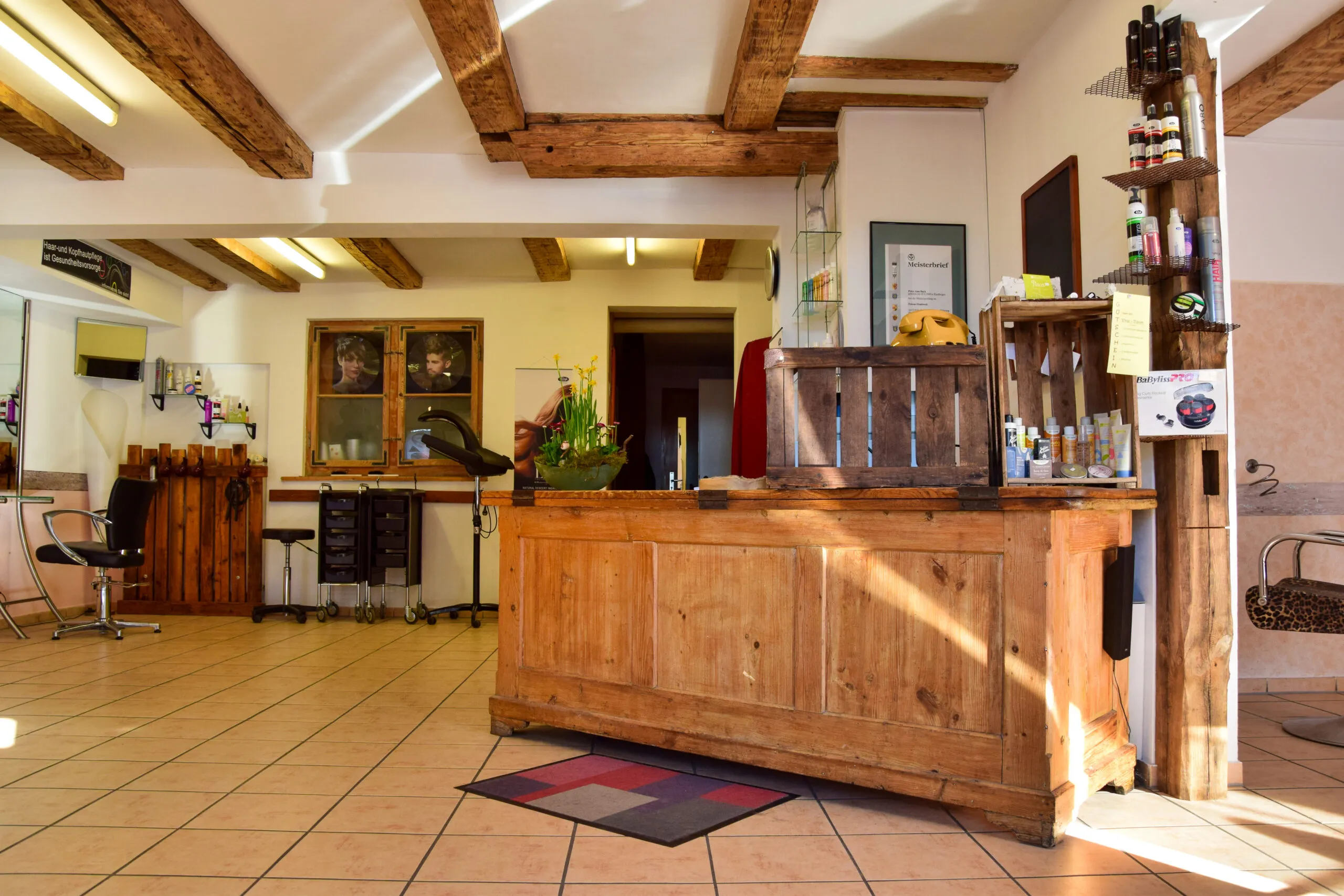 Friseur Salon P.E. — Empfangsbereich mit Holz-Theke und Naturlicht
